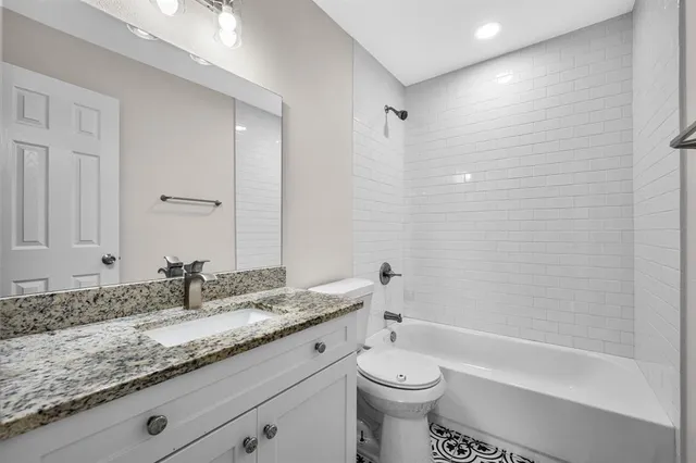 a bathroom with a granite countertop sink a toilet and bathtub