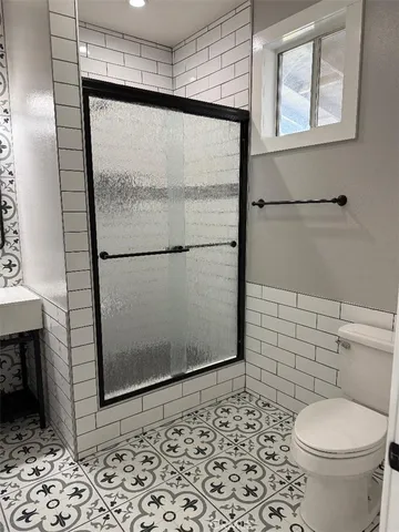 a bathroom with a toilet a window and a shower