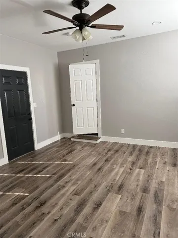 an empty room with wooden floor closet and windows