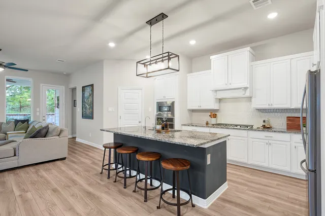 a living room with lots of furniture wooden floor and a chandelier