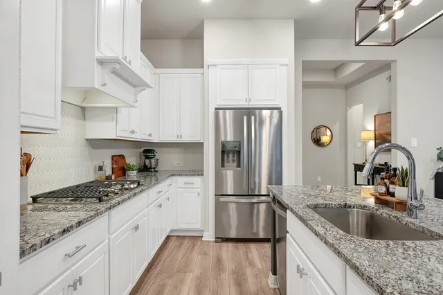 a kitchen with stainless steel appliances granite countertop hardwood floor sink stove dining table and chairs