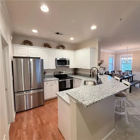 a kitchen with stainless steel appliances granite countertop a refrigerator a sink dishwasher a stove with wooden cabinets