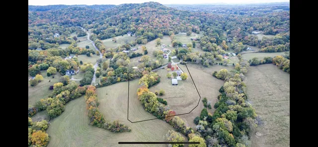 an aerial view of a house with a yard and mountain view in back