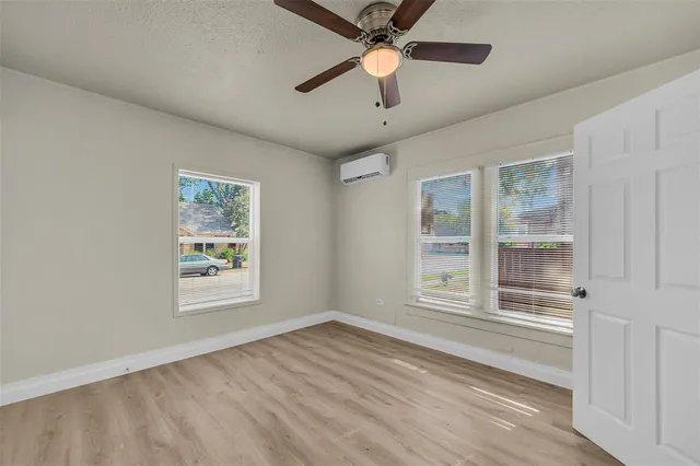 a view of an empty room with a window and wooden floor