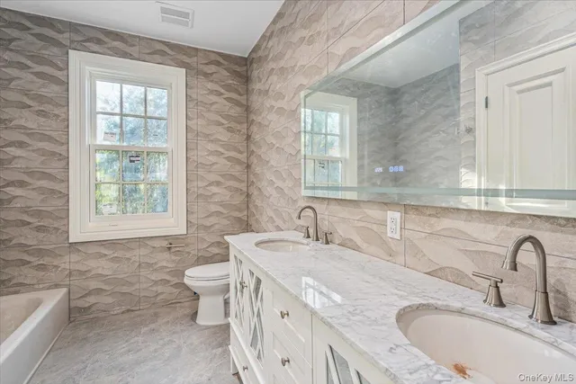 a bathroom with a granite countertop double vanity sink a mirror and a toilet