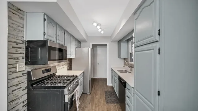 a kitchen with stainless steel appliances a stove top oven a refrigerator a sink and dishwasher