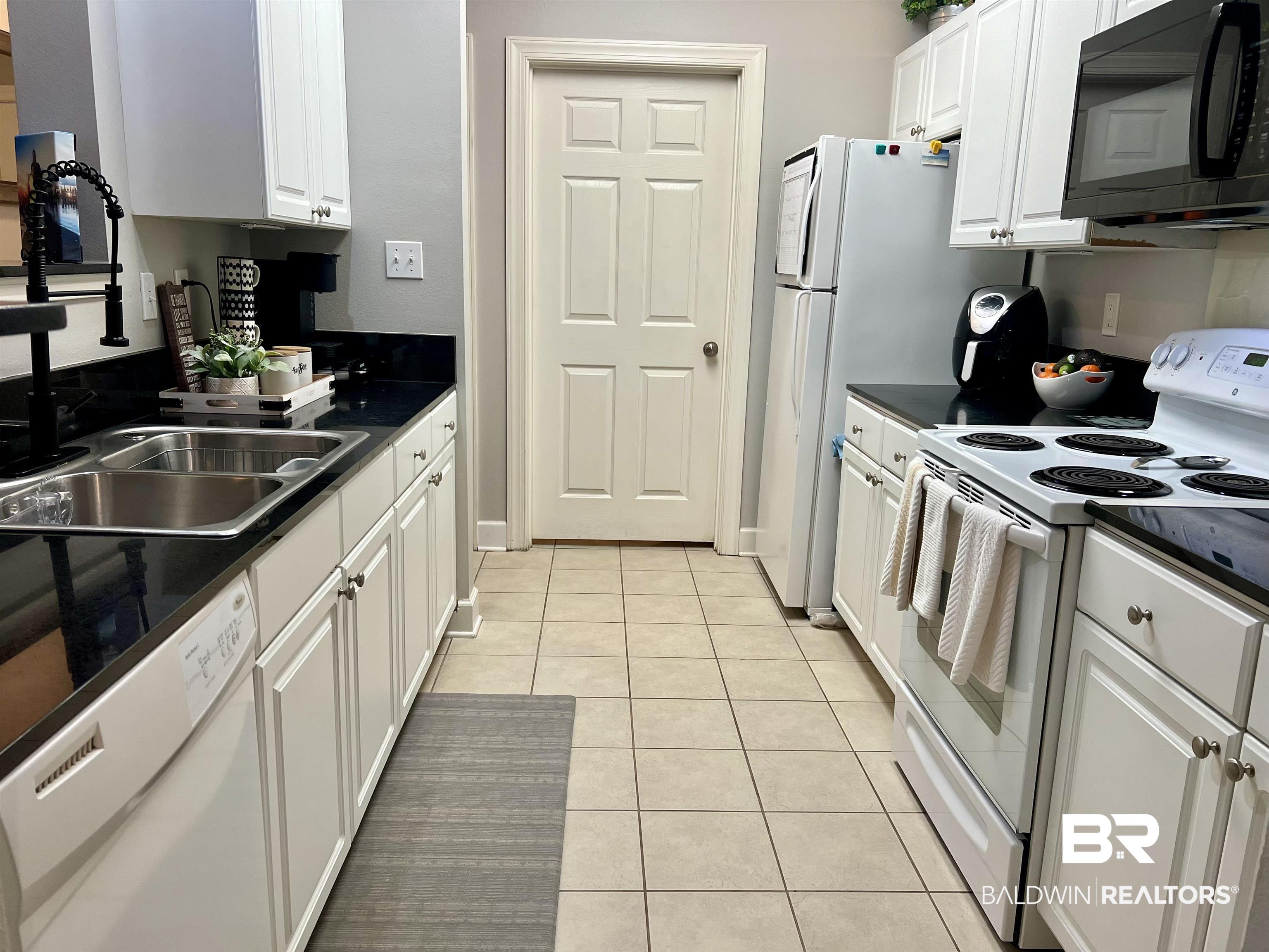 450 Park Avenue, Unit 808 Foley, AL 36535 - Photo 9 of 38 Kitchen featuring white appliances, light tile patterned floors, sink, and white cabinets