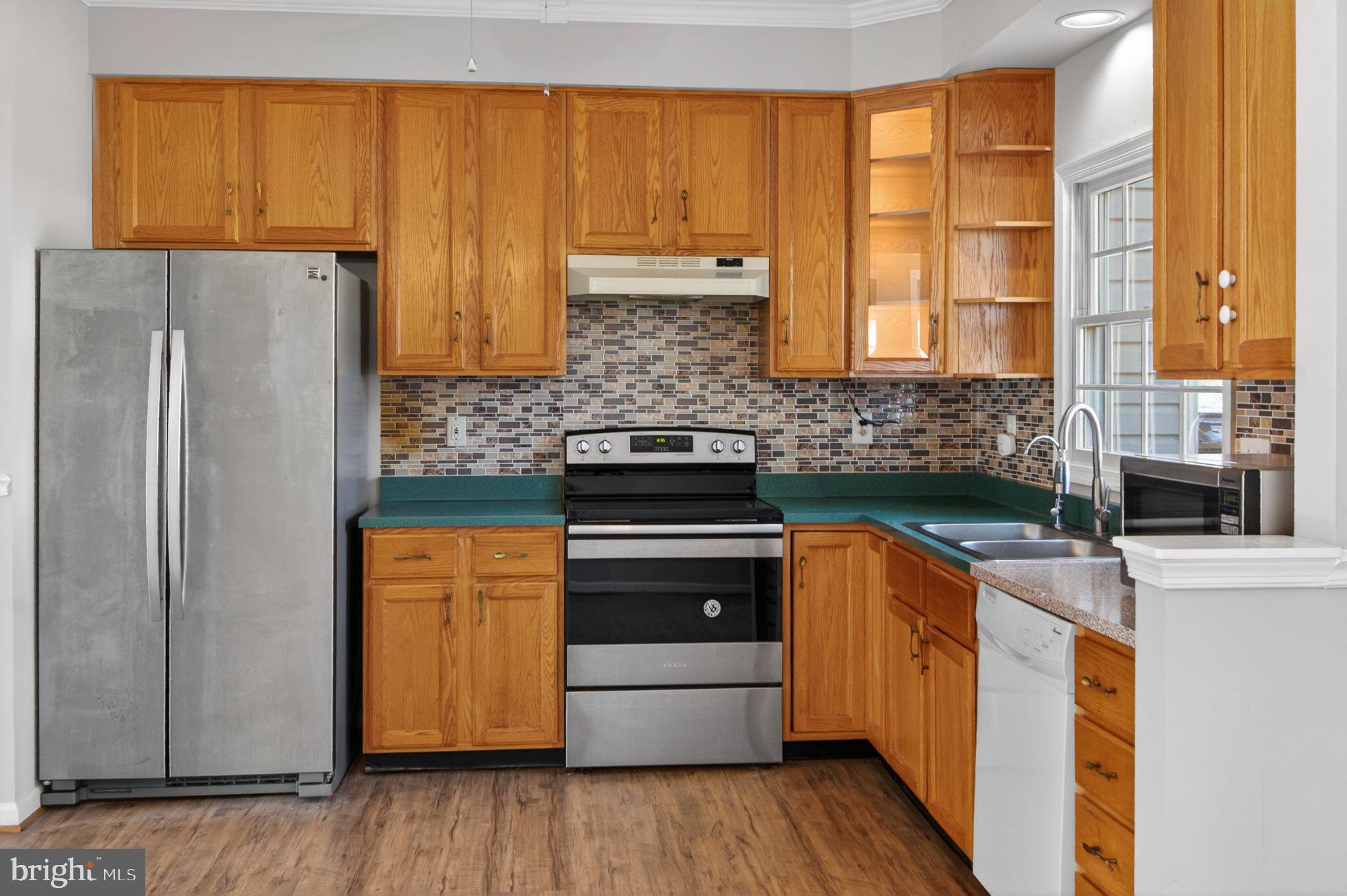 9963 Sherwood Farm Road Owings Mills, MD 21117 - Photo 17 of 48 a kitchen with stainless steel appliances granite countertop a refrigerator a sink dishwasher a stove and white countertops with wooden floor