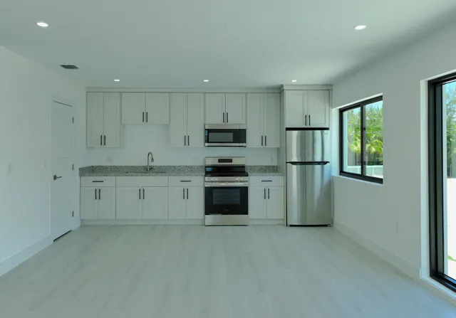 a kitchen with granite countertop white cabinets and stainless steel appliances