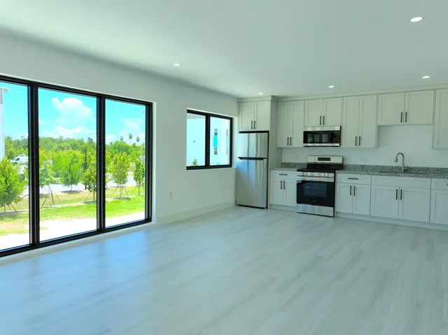 a open kitchen with stainless steel appliances granite countertop a stove a sink and a microwave