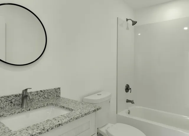 a bathroom with a granite countertop sink a toilet and shower