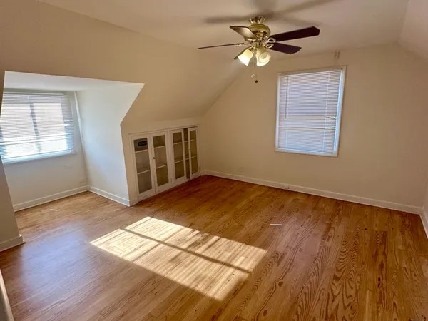 a view of an empty room with window and wooden floor