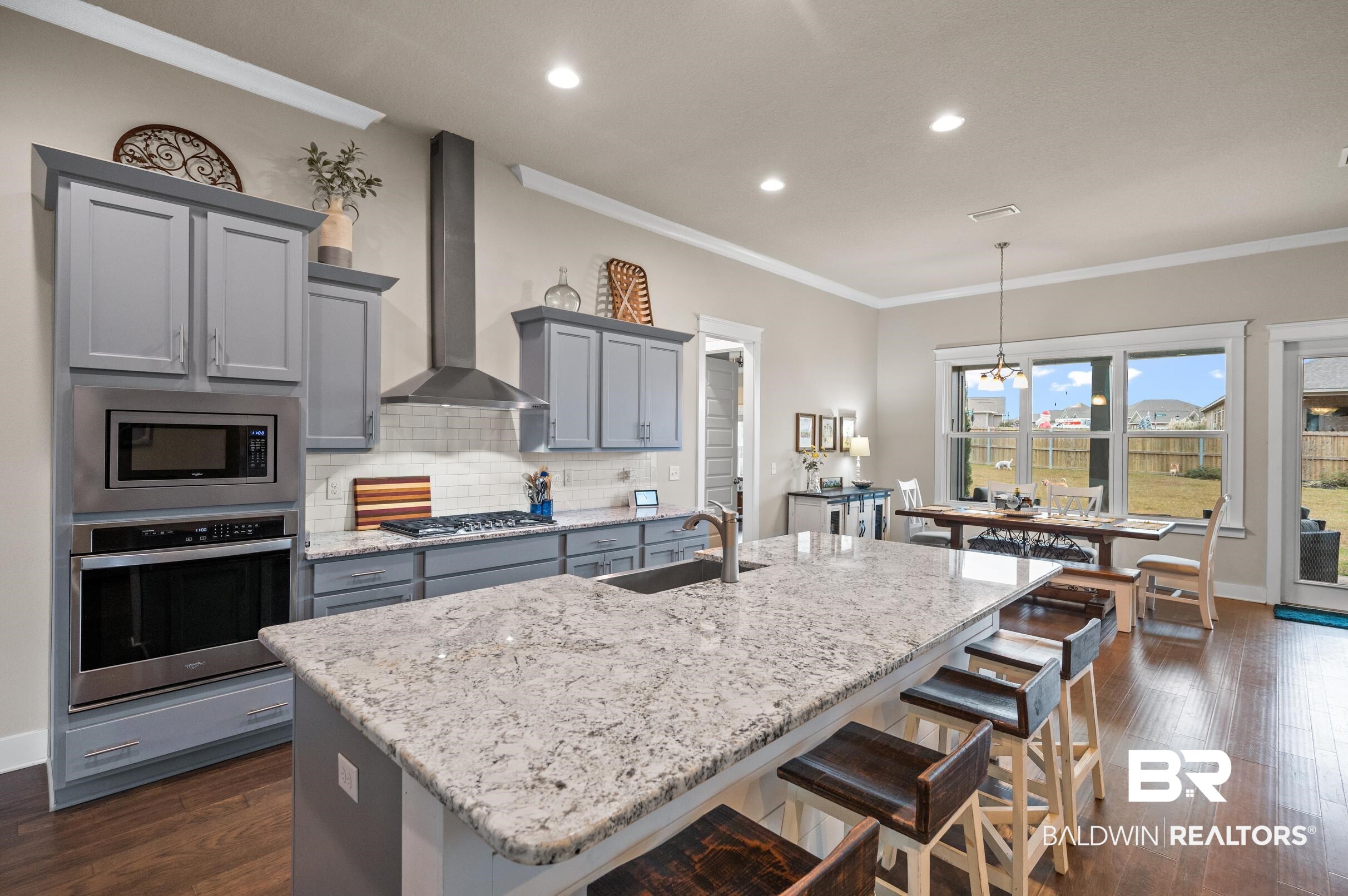 31355 Limpkin Street Daphne, AL 36527 - Photo 25 of 57 Kitchen with sink, wall chimney exhaust hood, pendant lighting, a kitchen island with sink, and appliances with stainless steel finishes