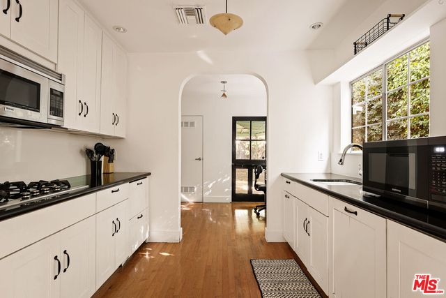 a kitchen with stainless steel appliances kitchen island granite countertop a stove a sink and a microwave