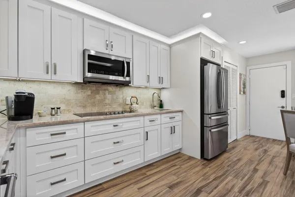 a kitchen with stainless steel appliances white cabinets and a stove top oven