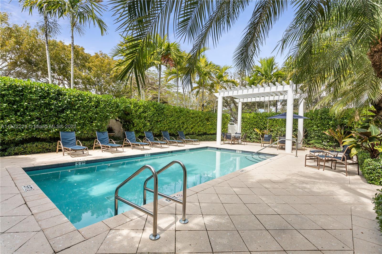 7682 Southwest 54th Avenue Miami, FL 33143 - Photo 29 of 37 a view of a swimming pool with a lawn chairs and palm trees