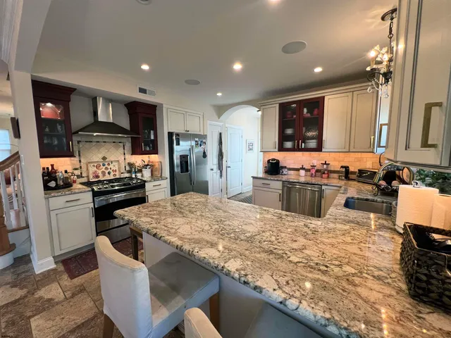 a kitchen with stainless steel appliances kitchen island granite countertop a stove and a refrigerator