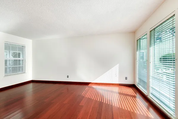 an empty room with wooden floor and windows