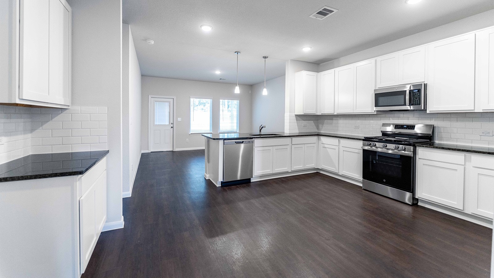 22003 Blue Sky Way New Caney, TX 77357 - Photo 10 of 15 a kitchen with stainless steel appliances kitchen island granite countertop a stove top oven a sink a refrigerator white cabinets and wooden floor