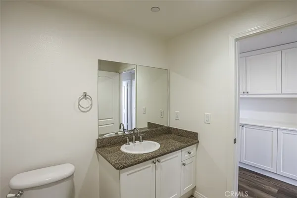 a bathroom with a granite countertop sink and a mirror with toilet