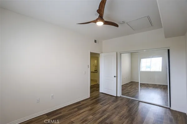 an empty room with wooden floor cabinet and windows