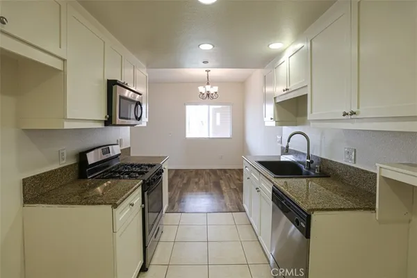 a kitchen with granite countertop a sink a stove and microwave