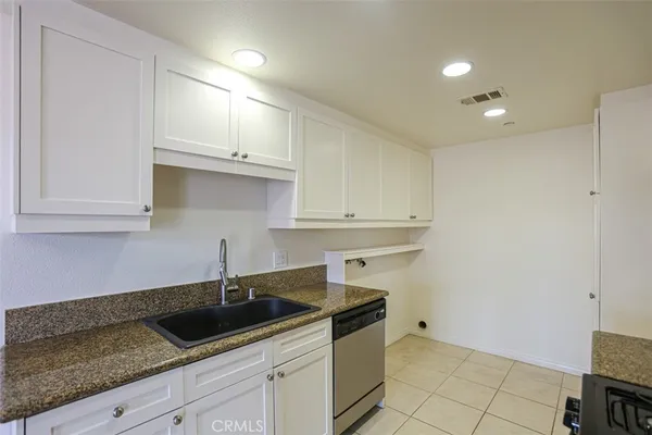 a kitchen with granite countertop white cabinets and a sink