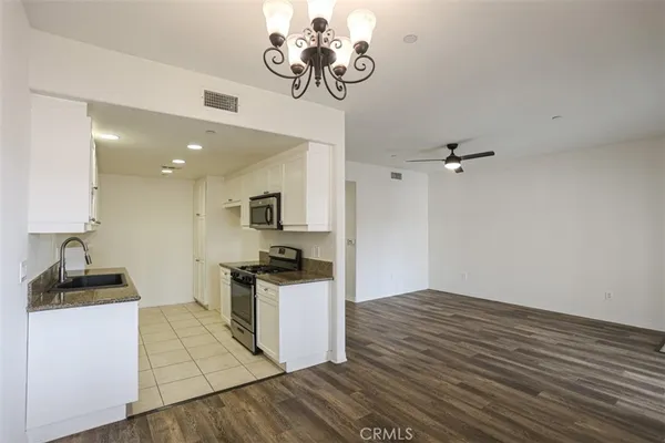 a kitchen with a refrigerator a stove top oven a counter space and wooden floor