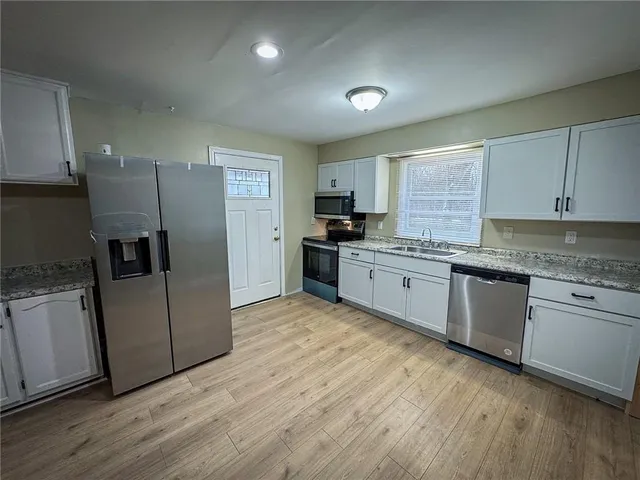 a kitchen with granite countertop cabinets stainless steel appliances a sink and wooden floor