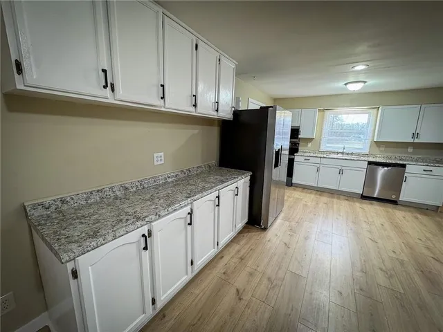 a kitchen with stainless steel appliances granite countertop a stove a sink and white cabinets