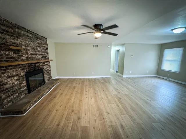 a view of empty room with wooden floor and fireplace