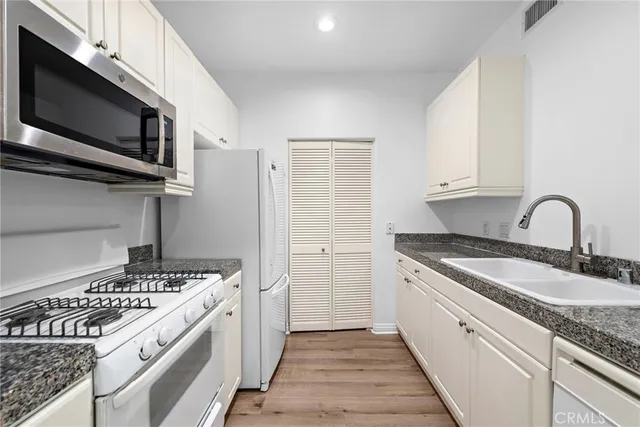 a kitchen with granite countertop a sink stainless steel appliances and cabinets