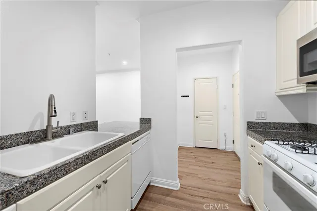 a kitchen with granite countertop a sink stove and cabinets