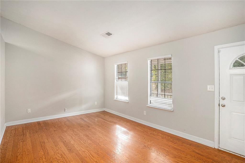 676 Tarkington Road South Stone Mountain, GA 30088 - Photo 3 of 20 an empty room with wooden floor and windows