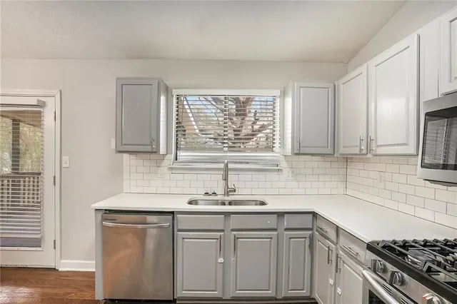 a kitchen with granite countertop a sink cabinets stainless steel appliances and a window