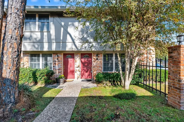 a view of a house with brick walls plants and large trees