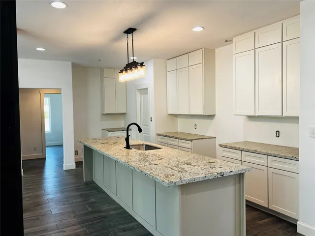 a kitchen with kitchen island granite countertop a sink a center island and stainless steel appliances