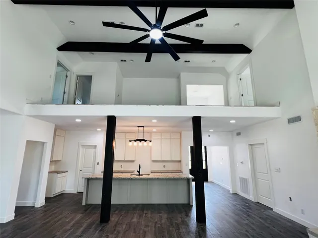 an empty room with wooden floor fan and windows
