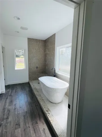 a walk in closet with wooden floor