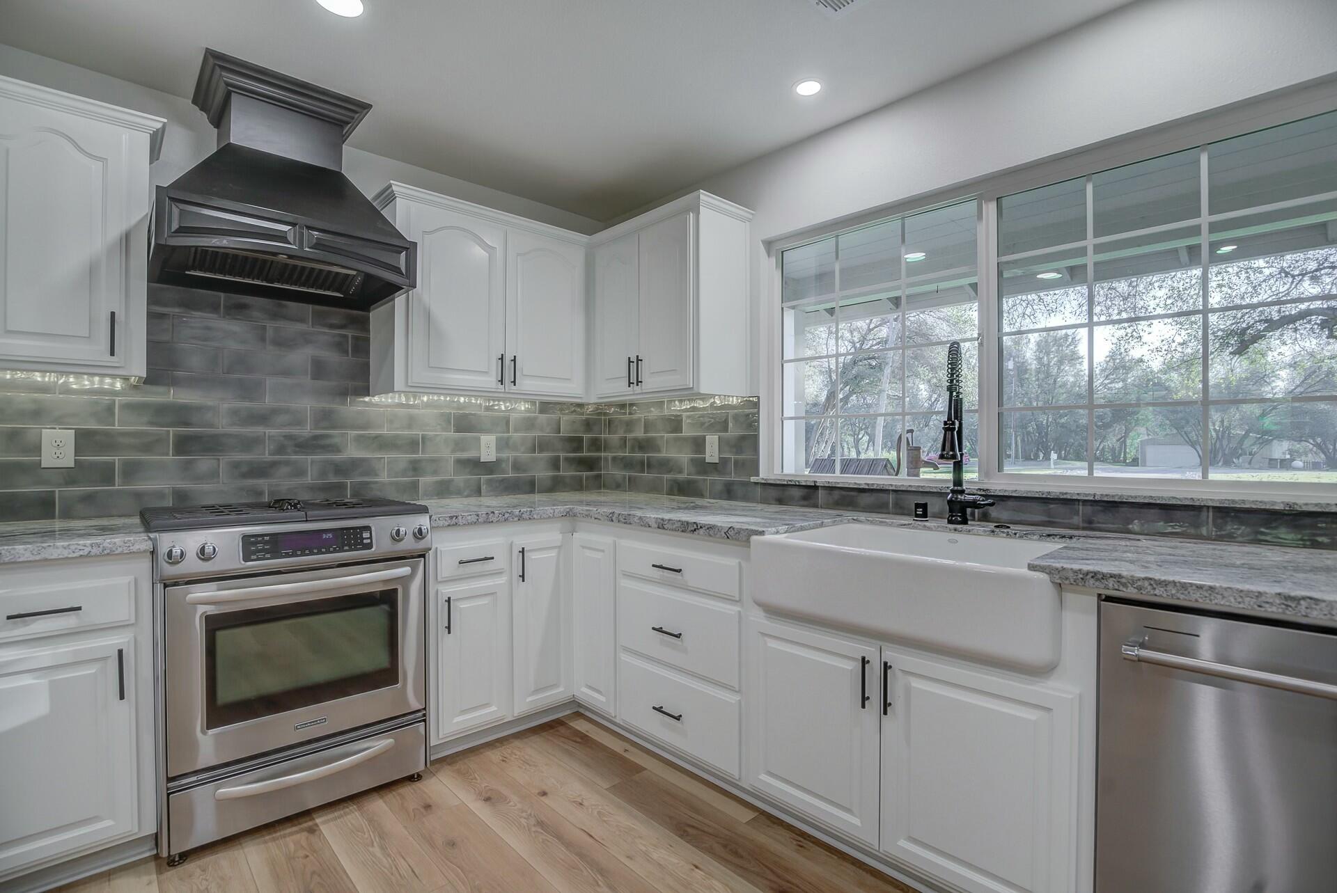 14300 Molluc Drive Red Bluff, CA 96080 - Photo 21 of 48 a kitchen with granite countertop a sink stainless steel appliances wooden floor and a counter top space