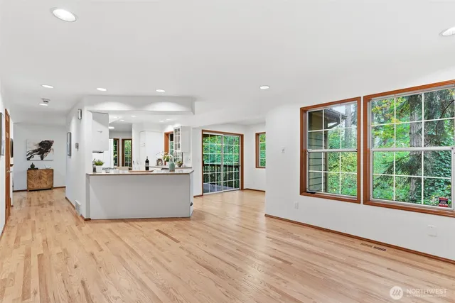 a living room with stainless steel appliances kitchen island hardwood floor and large windows