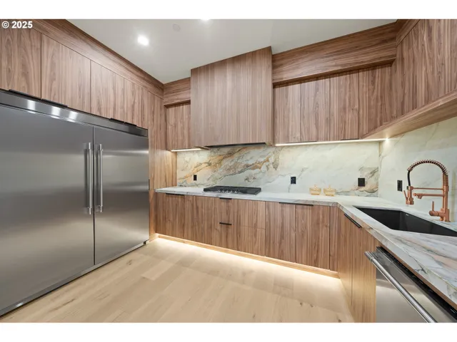 a kitchen with stainless steel appliances wooden cabinets a sink and a refrigerator