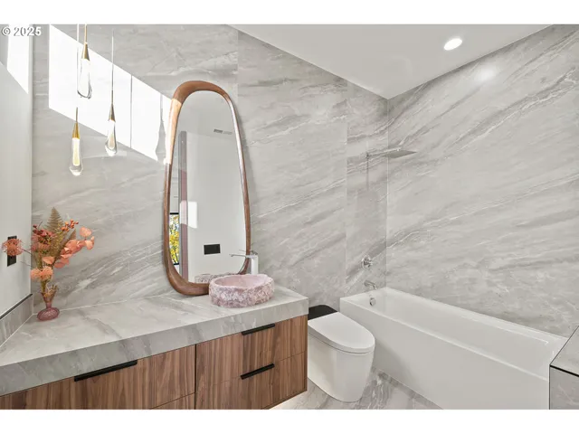 a bathroom with a granite countertop sink a toilet a shower and a mirror