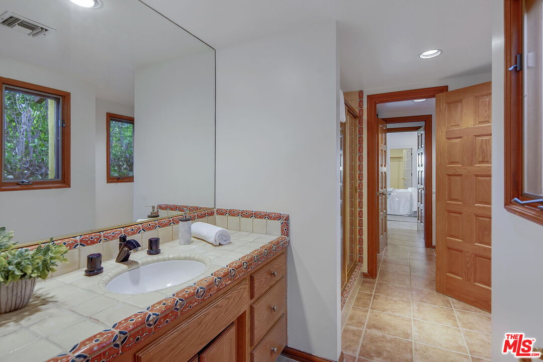 16814 Oak View Drive Encino, CA 91436 - Photo 31 of 49 a bathroom with a granite countertop sink and a mirror