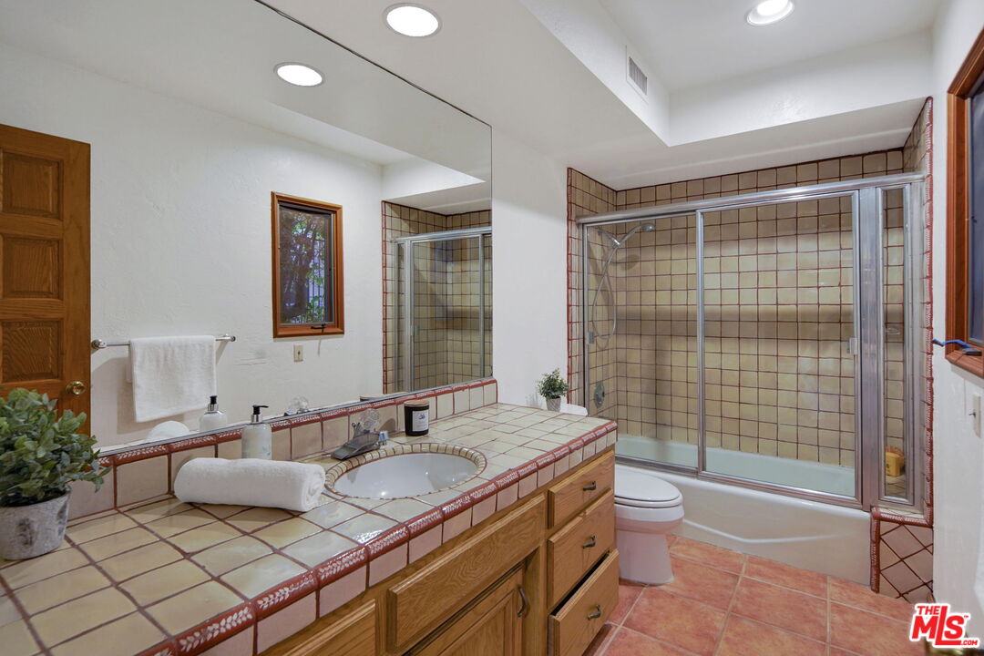 16814 Oak View Drive Encino, CA 91436 - Photo 35 of 49 a bathroom with a granite countertop double vanity sink a mirror and a bathtub