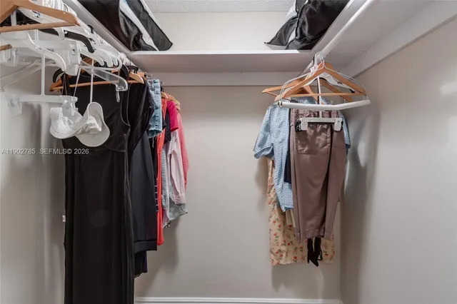 a view of walk in closet with clothes and shoes