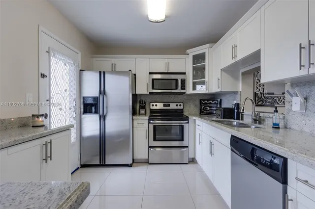 a kitchen with stainless steel appliances granite countertop a refrigerator sink and stove