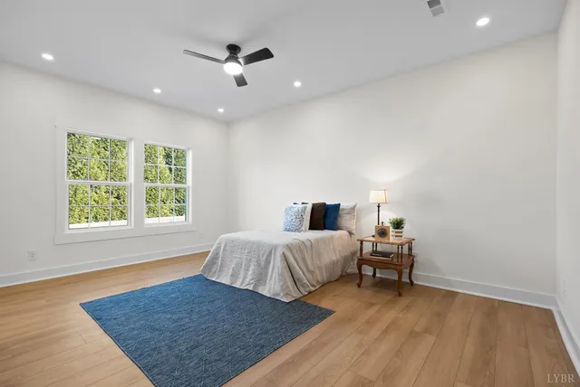 a view of an empty room with wooden floor and a ceiling fan