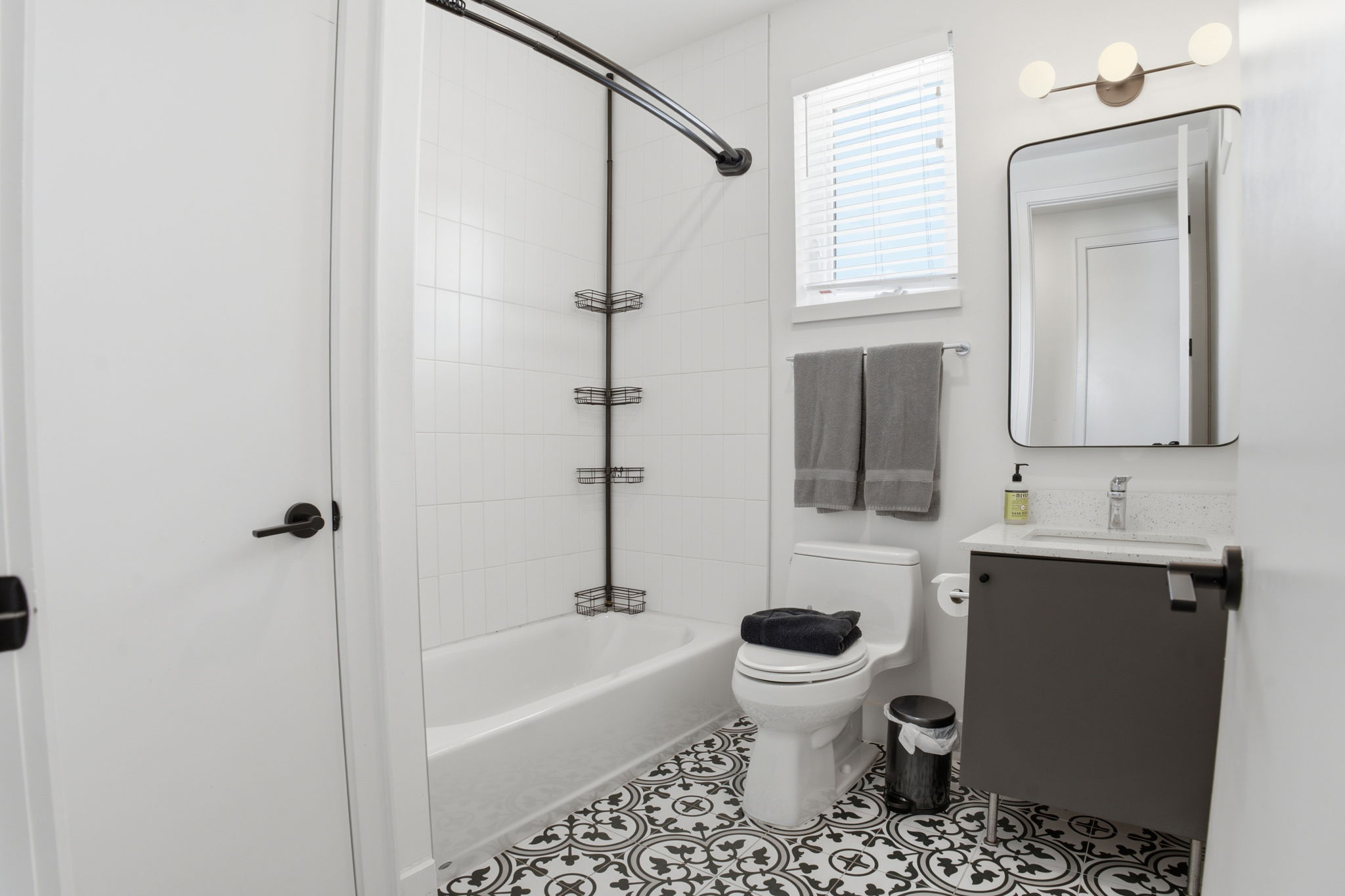 2709 East 5th Street, Unit 1306 Austin, TX 78702 - Photo 10 of 28 Black and white patterned tile flooring contrasts with crisp white walls in this well-lit bathroom.