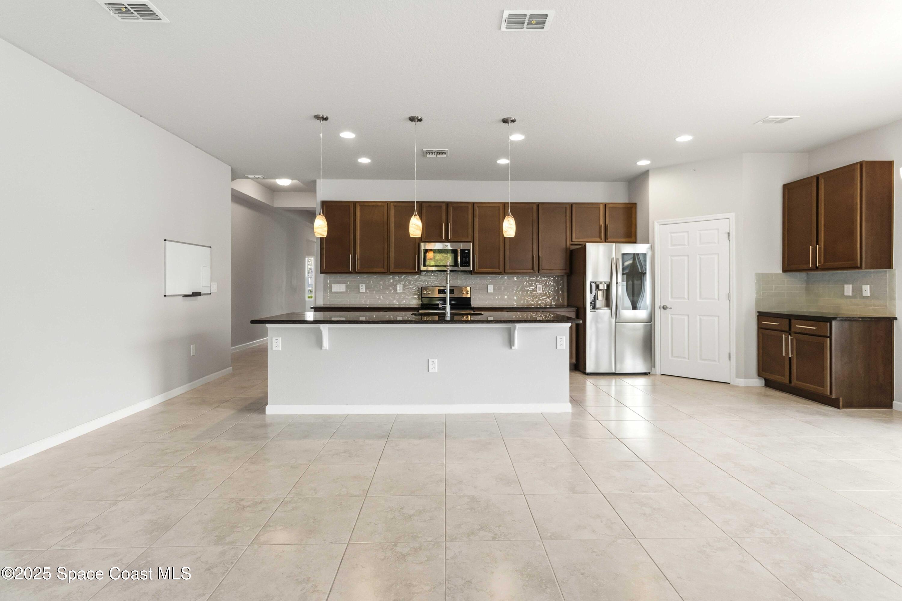 988 Corbin Circle Southwest Palm Bay, FL 32908 - Photo 5 of 26 a large kitchen with stainless steel appliances kitchen island a large counter top and a stove top oven